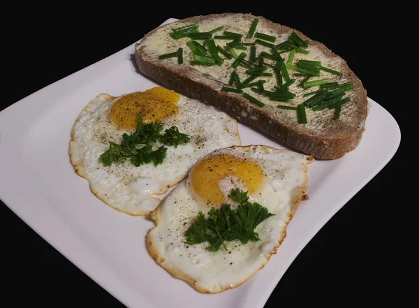 Жареные яйца с хлебом и маслом на белой тарелке — стоковое фото