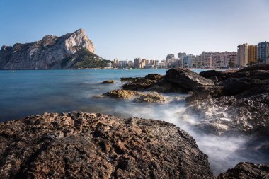 Sahil şeridinin kayalıklarından Calpe şehir plajına ve arka plandaki uçuruma bak, Alicante, İspanya