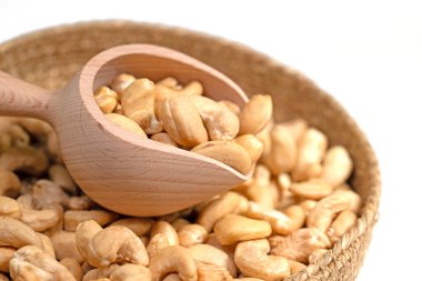 Beyaz arka planda kaju fıstığı ve baharat kepçesi