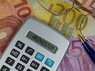 Taschenrechner mit dem Wort Heizkosten im Vor Geldscheinen 'i göster