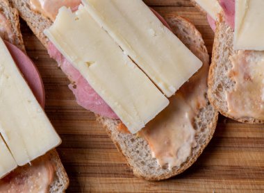 Tahta bir kesme tahtasının tepesinde otururken ikiye bölünmüş bir sandviç.