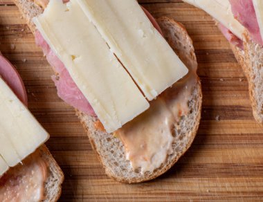 Tahta bir kesme tahtasının tepesinde otururken ikiye bölünmüş bir sandviç.