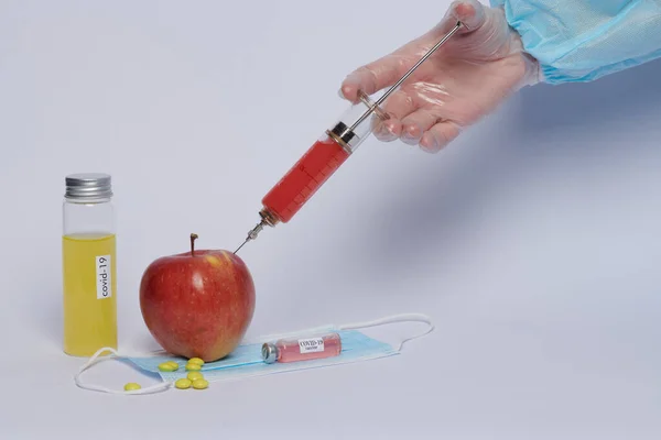 a doctor gives an injection of a vaccine into an apple