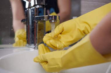 Sarı lastik eldivenlerle suyla ellerini yıka.