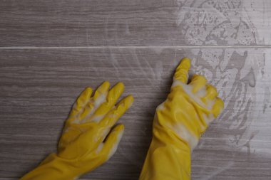 Sarı eldivenli sarı bir süngerle duvarı siliyorum.