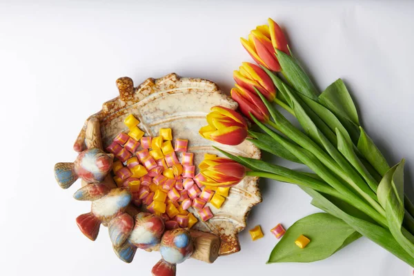 Een boeket van vijf tulpen op een achtergrond en een bord met vierkante snoepjes — Stockfoto