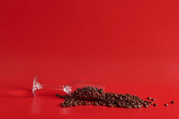 Skleněná a kávová zrna na červeném pozadí — Stock fotografie
