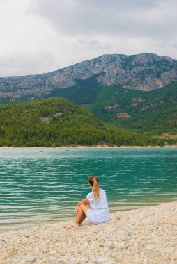 Bir su kütlesinin yanında duran biri.