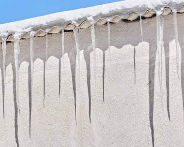 Evin çatısında bir sürü buz saçağı var.