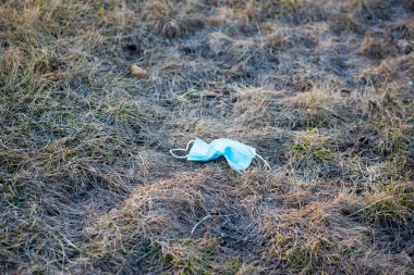 Eski bir tıbbi maske çimlerin üzerinde yatıyor.