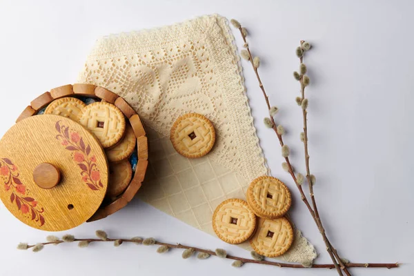 Op een witte achtergrond wilgentwijgen en een kopje met ronde koekjes op een servet — Stockfoto