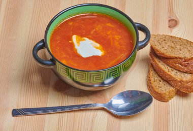 Kırmızı çorba ve üç dilim ekşi krema.