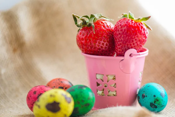 Huevos de Pascua y fresas en un cubo rosado — Foto de Stock