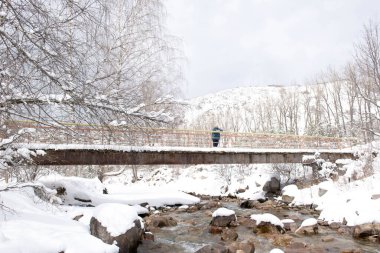 Bir dağ nehri üzerindeki köprüde bir kadın.