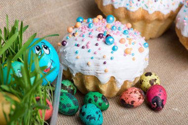 Büyük Paskalya pastası ve renkli yumurtalar arka planda yatıyor.