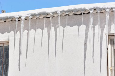 Buz saçaklarından bir evin çatısında.