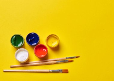 Sarı arka planda birkaç fırça ve parlak boya var.