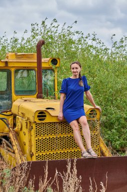 Sarı traktör ve mavi elbiseli bir kız.