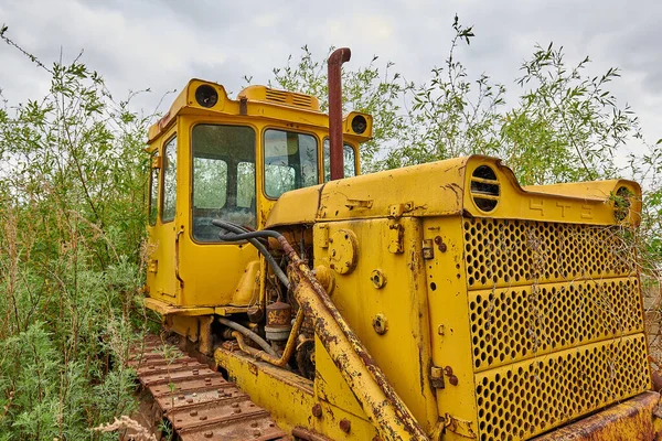 Gammel brudt gul traktor på grønne baggrund - Stock-foto