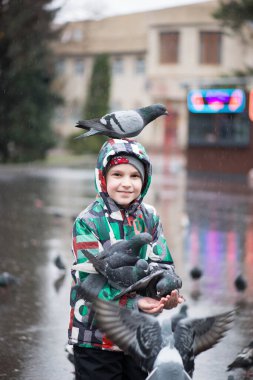 Neşeli çocuk ve güvercinler yağmurda parkta
