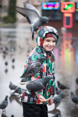 Çocuk ve güvercinler yağmurda parkta