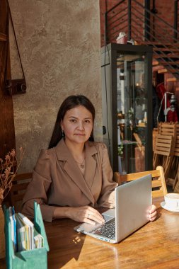 Bir kadın kafede bir masada çalışıyor.