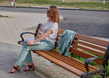 Bankta oturan gri dizüstü bilgisayarlı iş kızı.