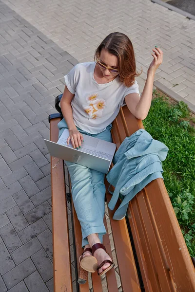 Chica emocional que trabaja en un banco en un ordenador portátil — Foto de Stock