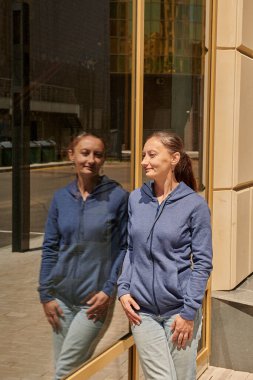 Kafenin vitrininde süveter giyen bir kız duruyor.