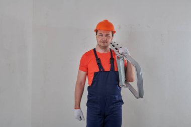 Elinde merdiven tutan mavi tulumlu bir elektrikçi.