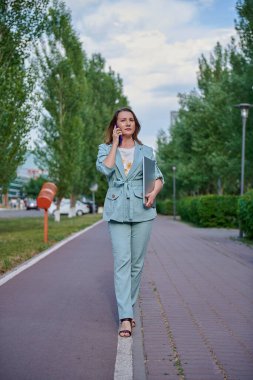 Kaldırımda elinde telefonla yürüyen bir kadın.