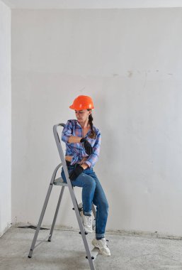 Miğferli bir kız merdivende oturur.