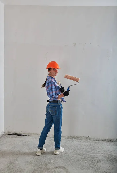 Un constructeur dans un casque de construction avec un rouleau et des brosses — Photo