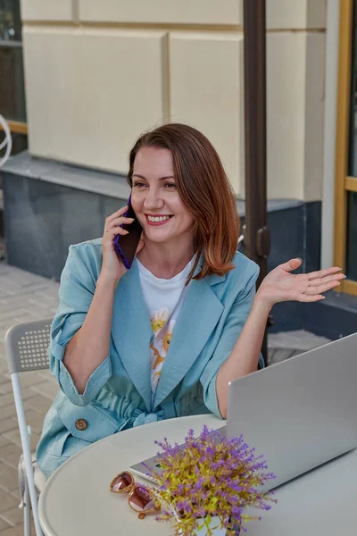 Hablando de una chica pelirroja por teléfono en un café — Foto de Stock