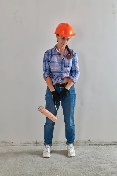 Dans un casque, un réparateur avec un rouleau de peinture est — Photo