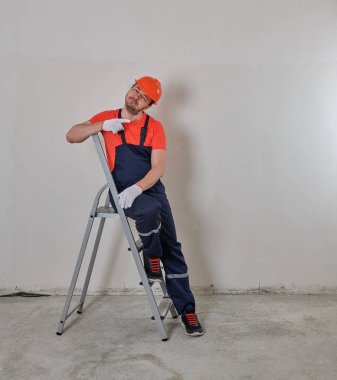 Neşeli tamirci miğferli bir merdivende oturur.