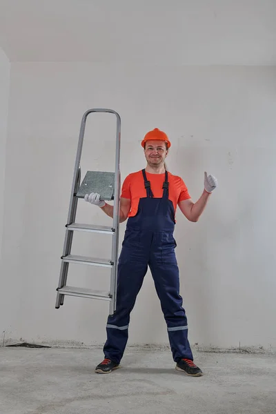 Un constructor experimentado sostiene una escalera en una mano —  Fotos de Stock