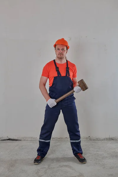 Travailleur avec un marteau de traîneau dans ses mains dans un casque orange — Photo