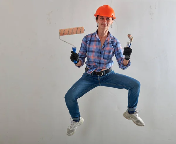 Vrolijke schilder in oranje helm en roller — Stockfoto