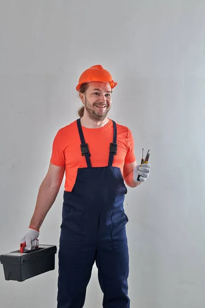 В оранжевом шлеме, мастер с инструментами стоит — стоковое фото