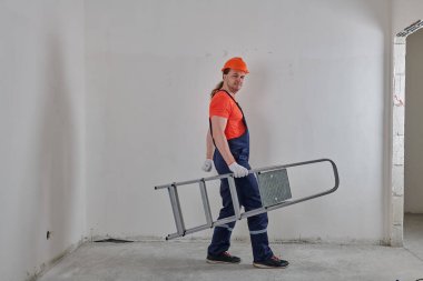 Önemli bir mühendis kolunun altında bir merdiven tutuyor.