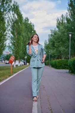 Bir kız yolda yürüyor ve konuşuyor.