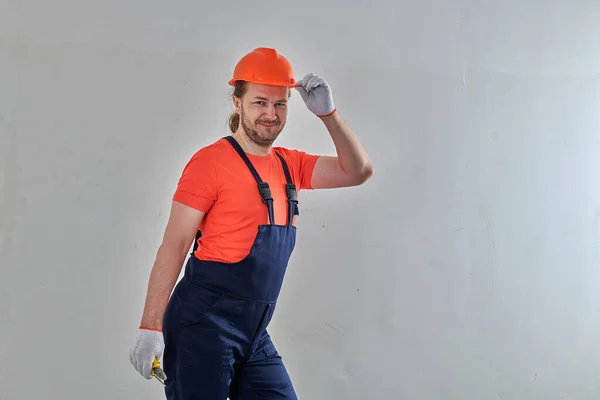 Orange hard hat repair master stands against white wall background — стоковое фото