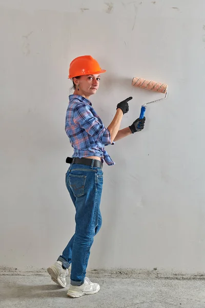 In an orange helmet, a foreman works with a roller — стоковое фото