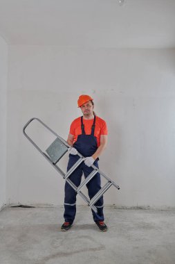 Neşeli pompalı tamirci başının üstünde bir merdiven tutuyor.