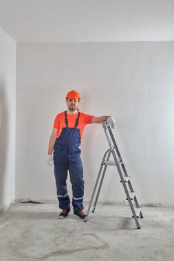 Bir ustabaşı miğferli bir merdivenin başında durur.