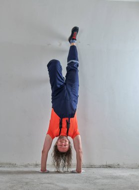 Turuncu tişörtlü komik ustabaşı baş aşağı duruyor.