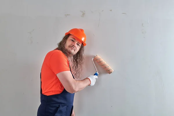 Художник в яркой футболке стоит у стены с роликом — стоковое фото