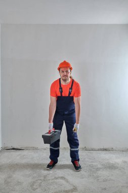 Elinde alet çantası olan yorgun bir elektrikçi.