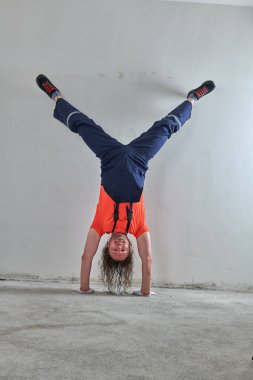 Turuncu tişörtlü orijinal ustabaşı baş aşağı duruyor.